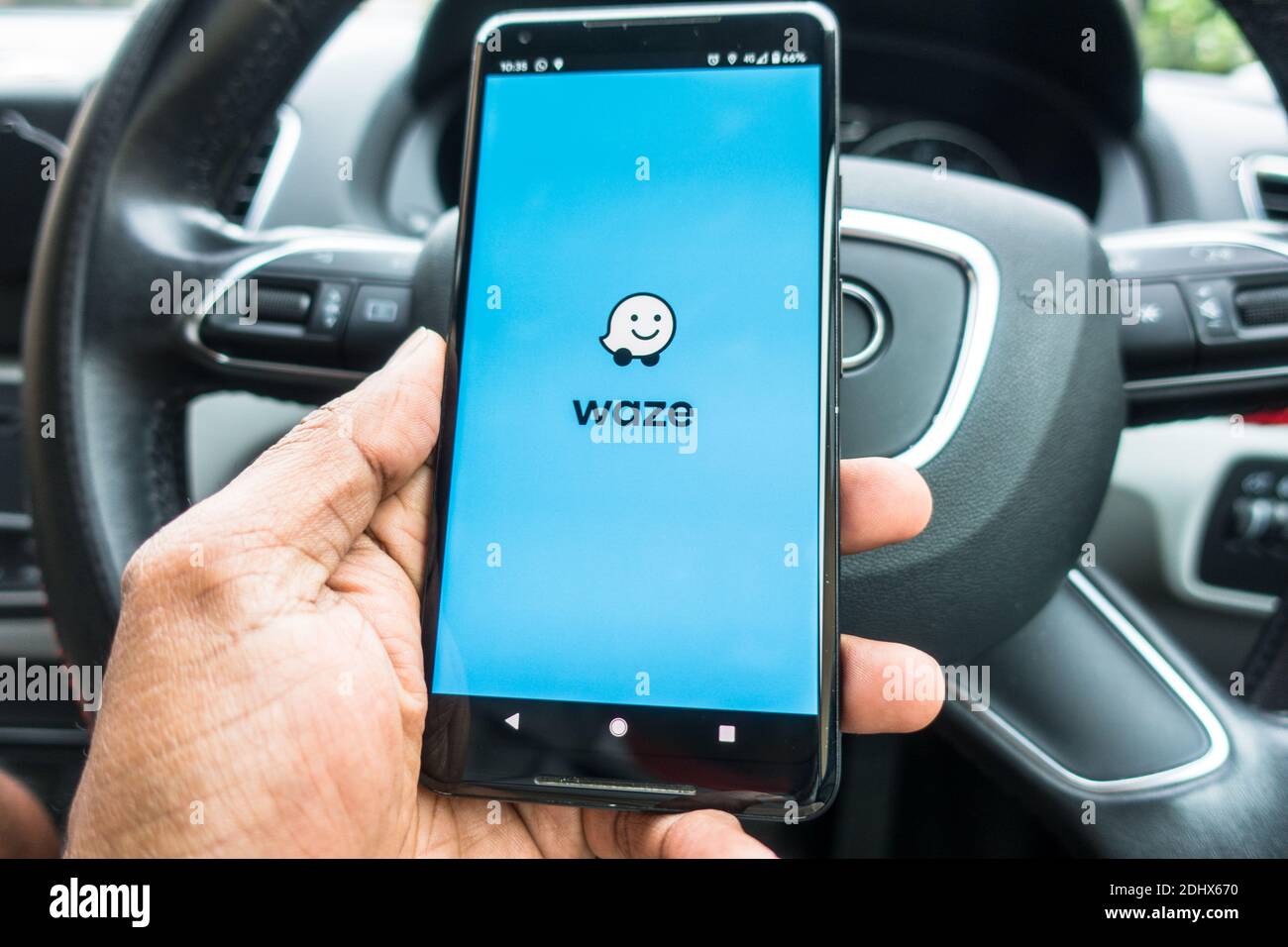 Waze direction application on mobile phone in car with steering wheel Stock Photo