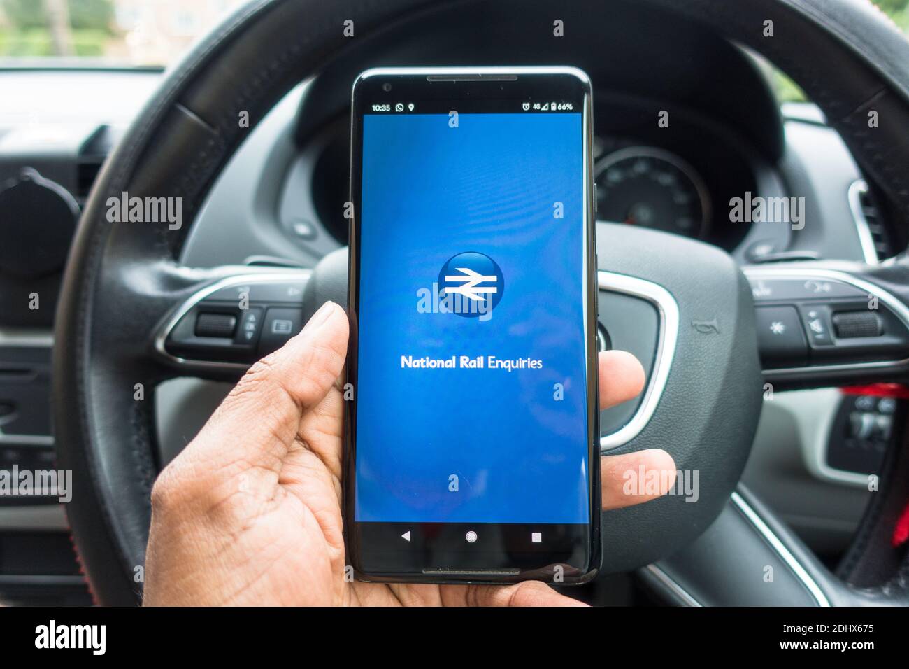 Person opening National rail app from Car with steering wheel visible Stock Photo