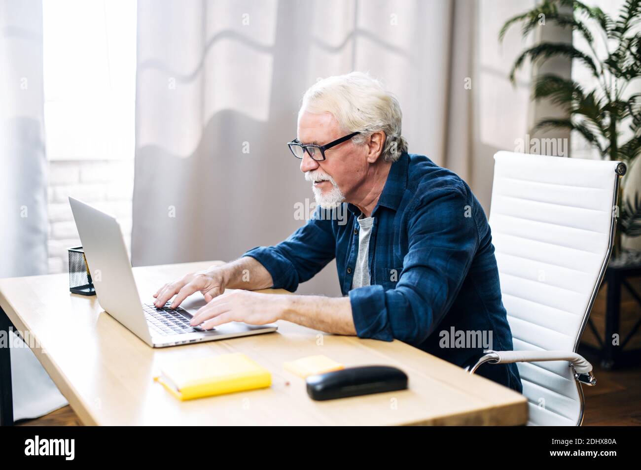 Older man is using laptop for working indoor Stock Photo