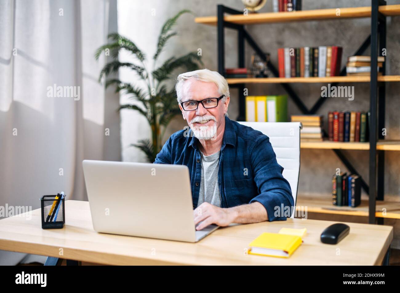 Older man is using laptop for working indoor Stock Photo
