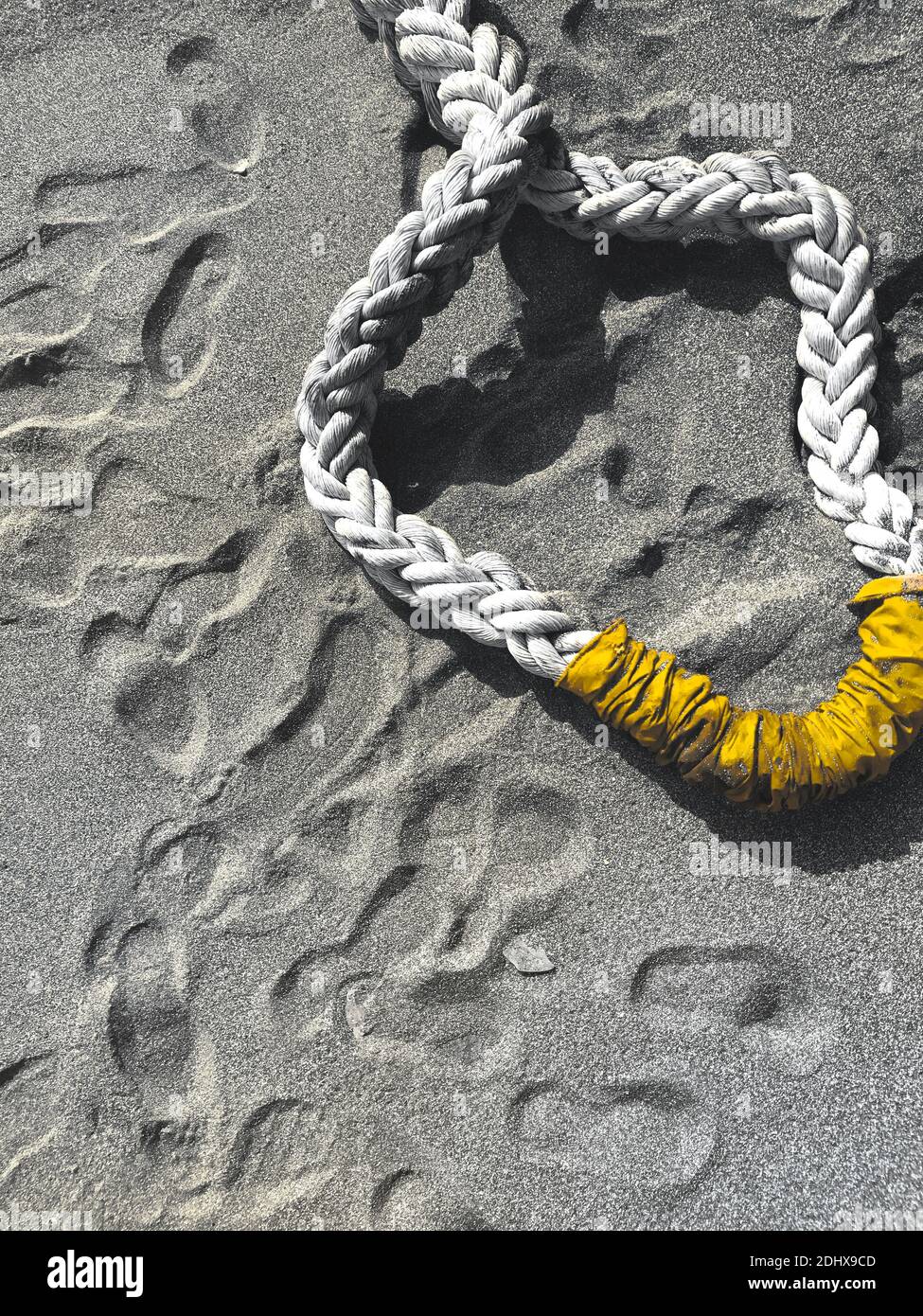 Grey sandy beach with yellow colored ship rope and footprints on the ground. Abstract background for marine concept illustration with text space Stock Photo