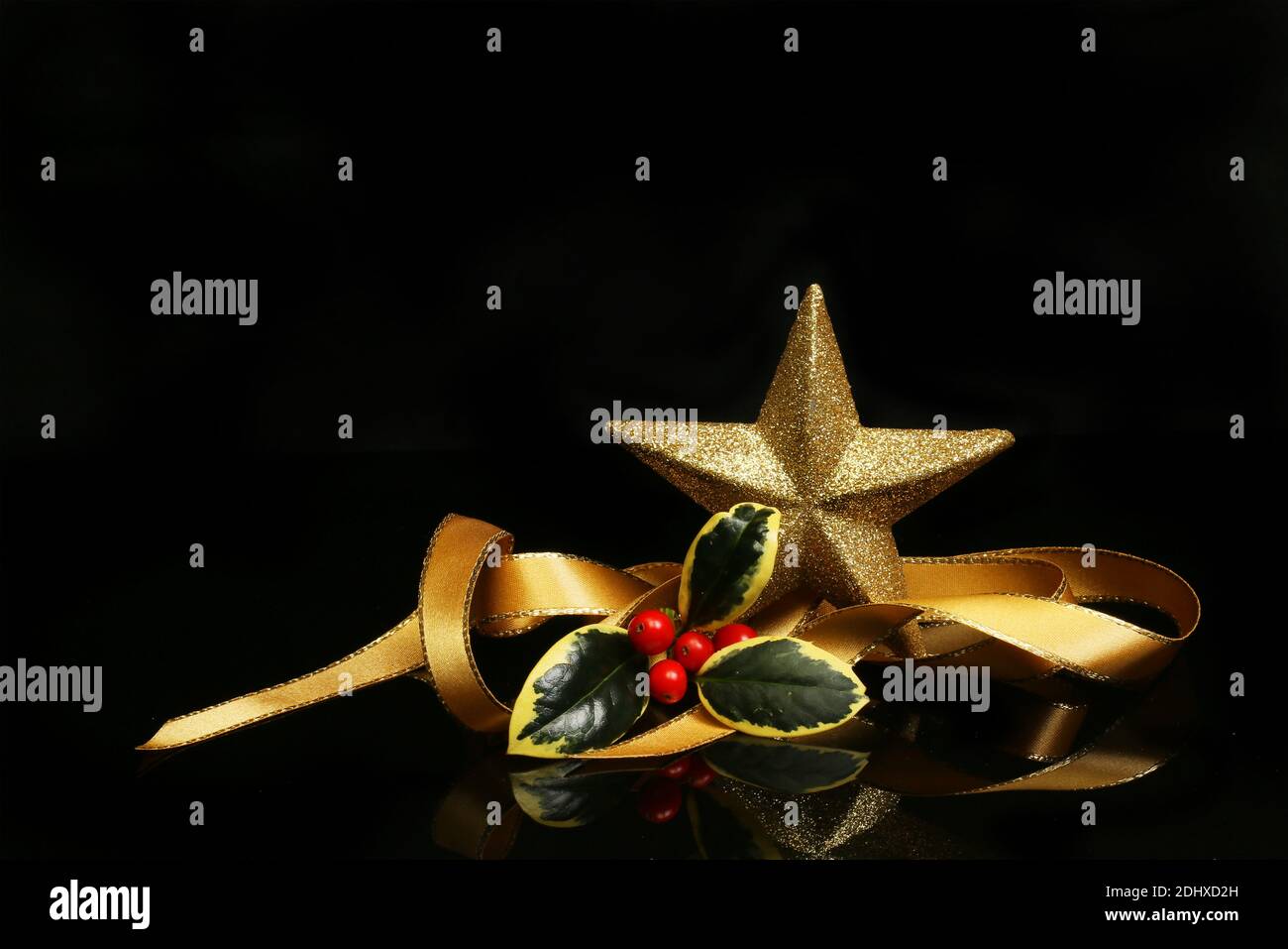 Christmas decoration, coiled gold ribbon with holly and a gold glitter ...