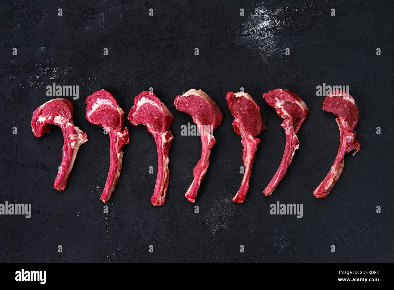 Composition with rack of lamb, seasoning and herbs on dark background