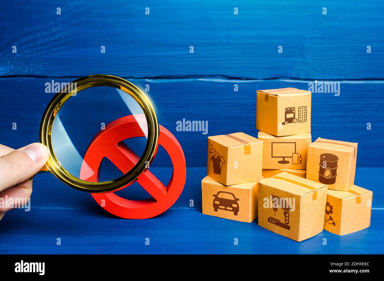 Man with a magnifying glass examines red prohibition sign NO near boxes. Assessment of damage from sanctions or embargo. Effect of restrictive measure Stock Photo