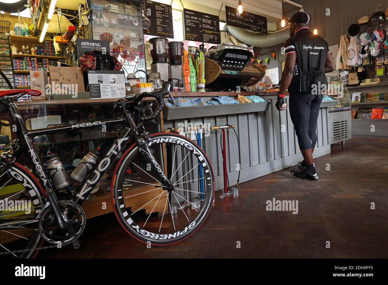 man enjoying a cup of coffee at a cafe in the city while his bike stands next to him at cycling cafe Look Mum No Hands in London,UK Stock Photo
