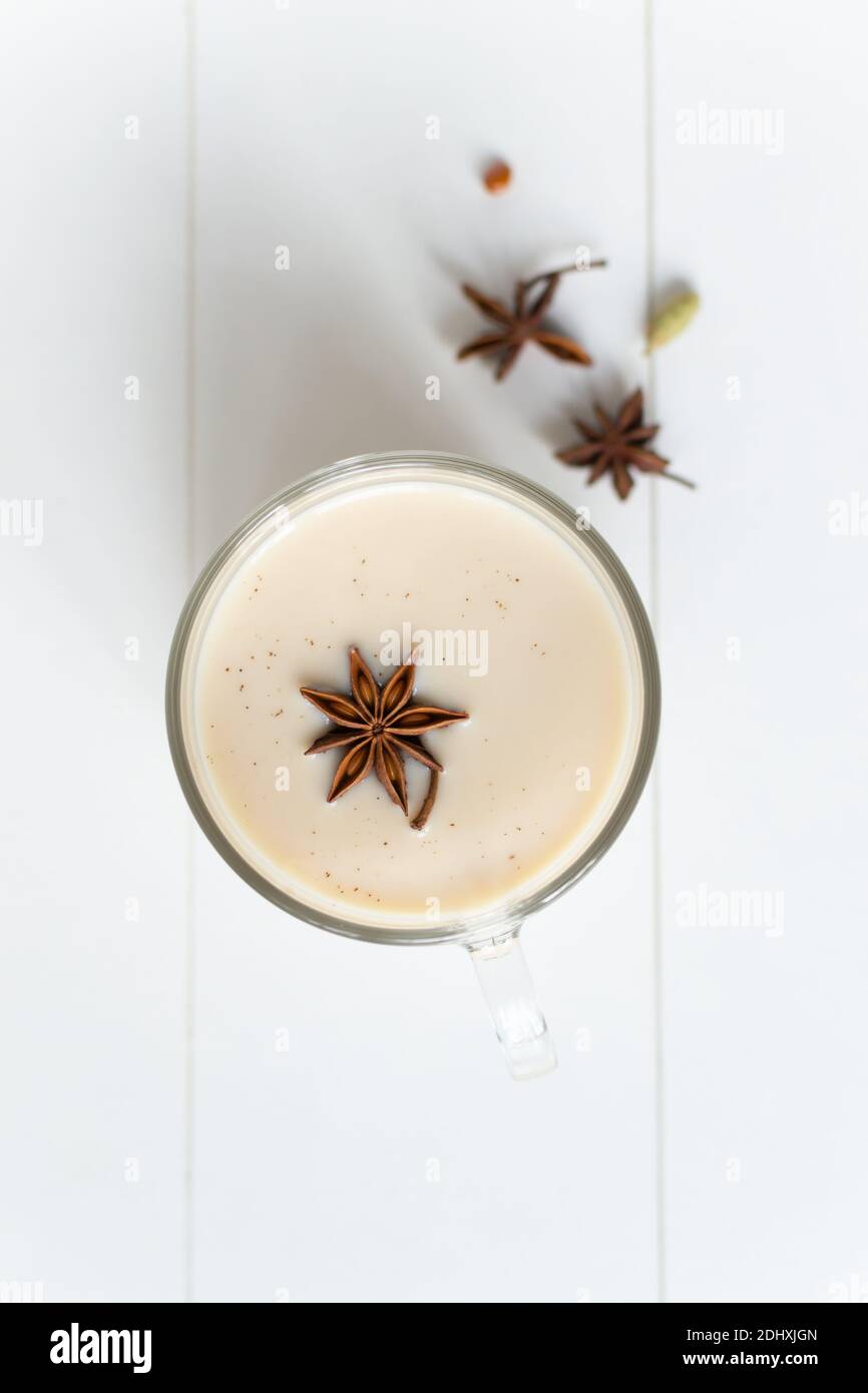 Masala tea in a glass cup with spices and anise star on a white ...