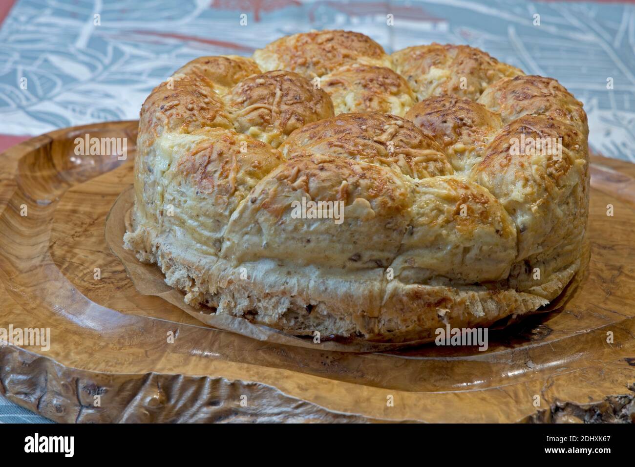 Freshly baked homemade cheese bread ring on wooden olive bread board