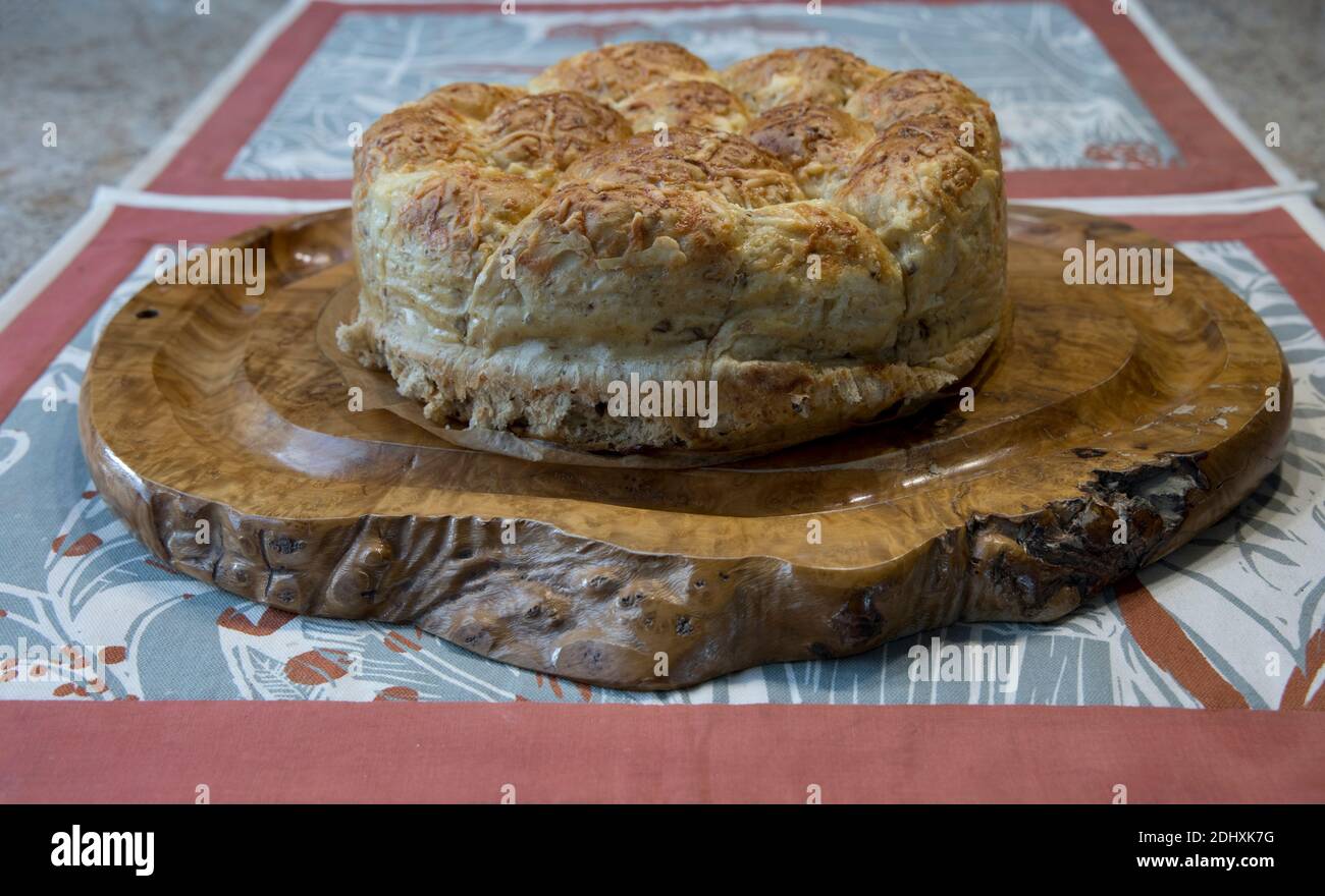 Freshly baked homemade cheese bread ring on wooden olive bread board