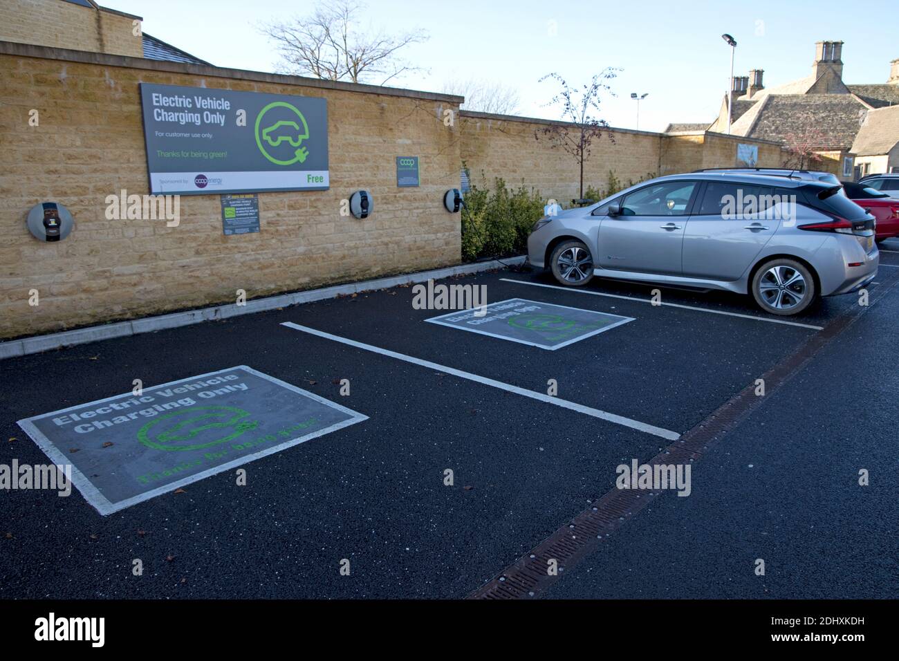 Electric vehilce charging points are Coop Supermarket Chipping Campden with Nissan Leaf on charge Stock Photo