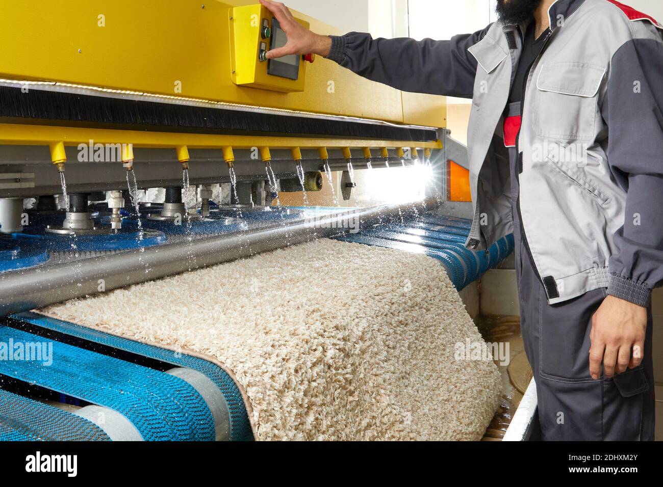 Man operating carpet automatic washing machine in professional laundry