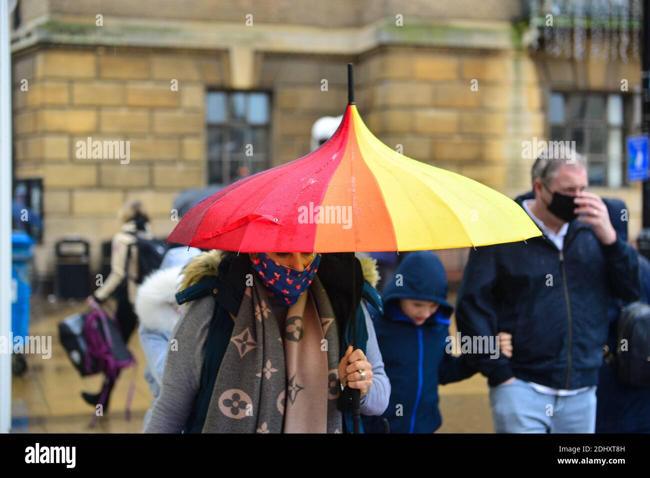 cambridge uk, 12122020, Female shelters under multi coloured umbrella