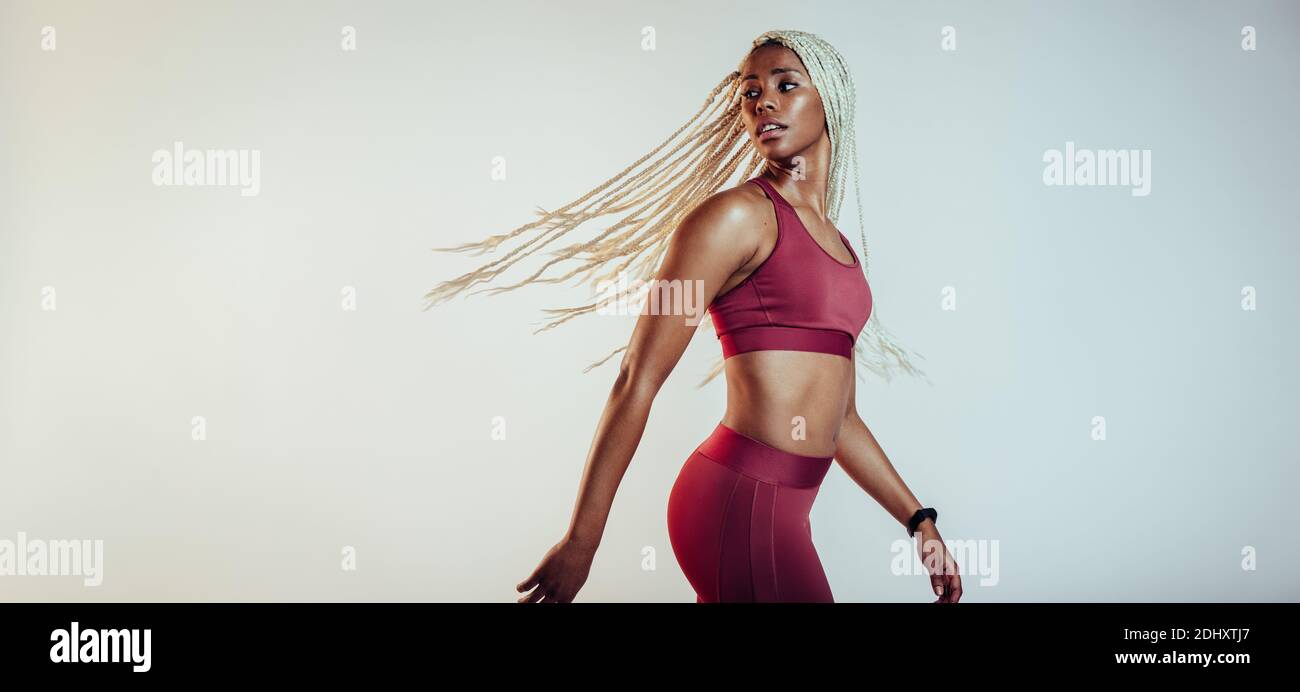 Fit female athlete looking over shoulder during workout. African american athlete doing fitness workout on white background. Stock Photo