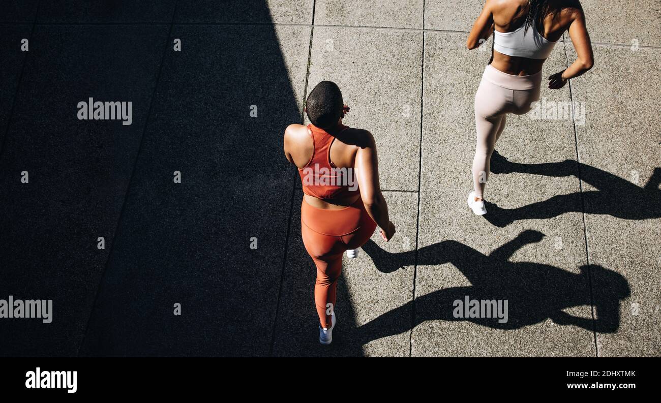 Top view of a two women in running attire jogging together. Female  friends working out together in morning. Stock Photo