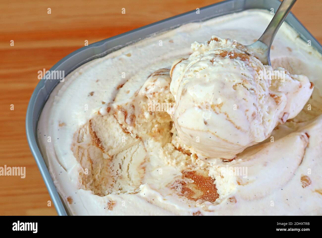 Closeup of a Spoon Scooping Delectable Caramel Macadamia Nut Ice Cream in the tub Stock Photo