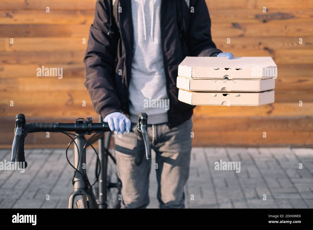 Bike delivery person holds pizza boxes in hand. Food delivery, bicycle courier at work, takeaway catering concept Stock Photo