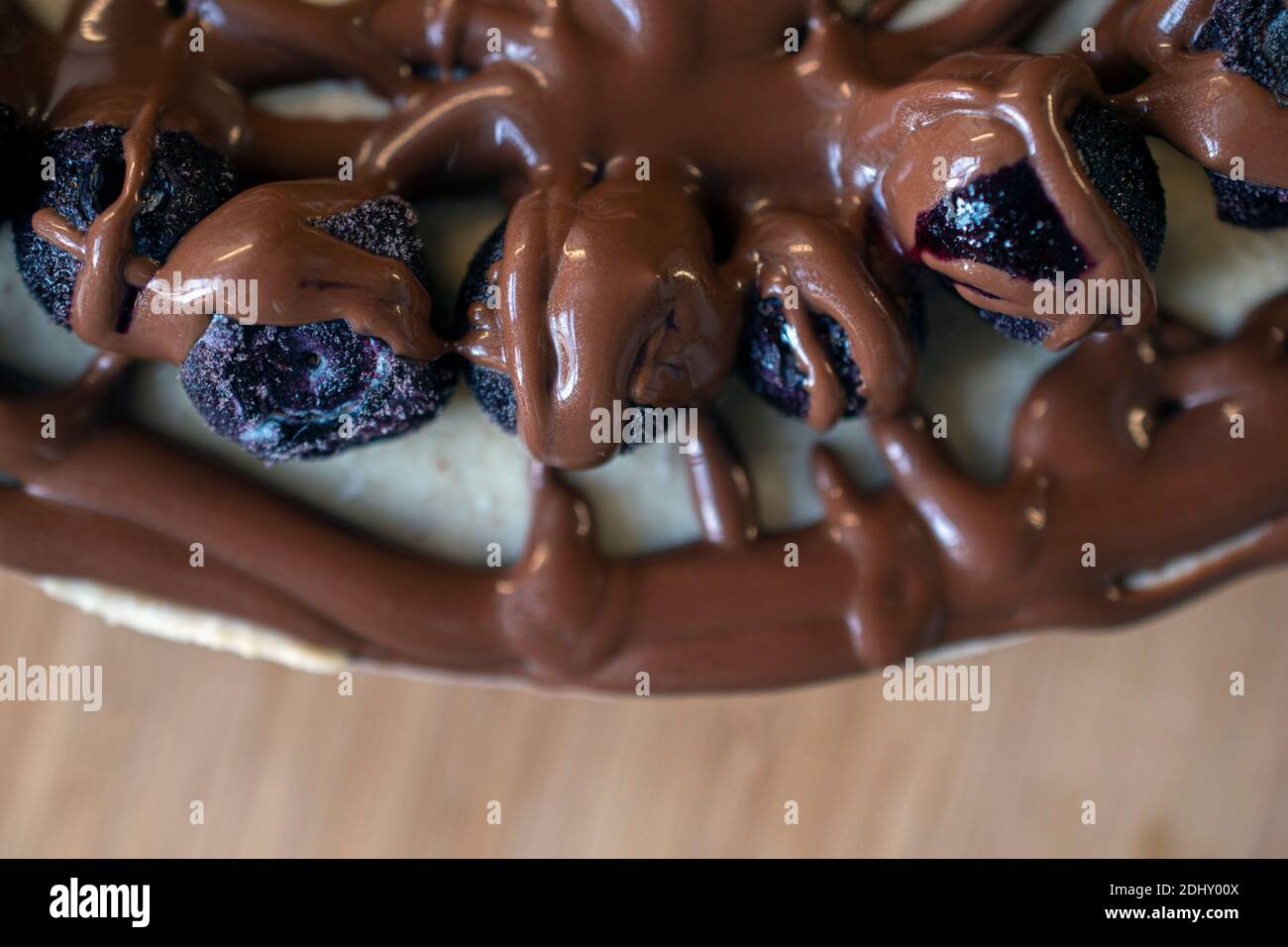 Delicious and decadent layered cheesecake dessert topped with fresh blueberries and drizzled with melted chocolate topping Stock Photo