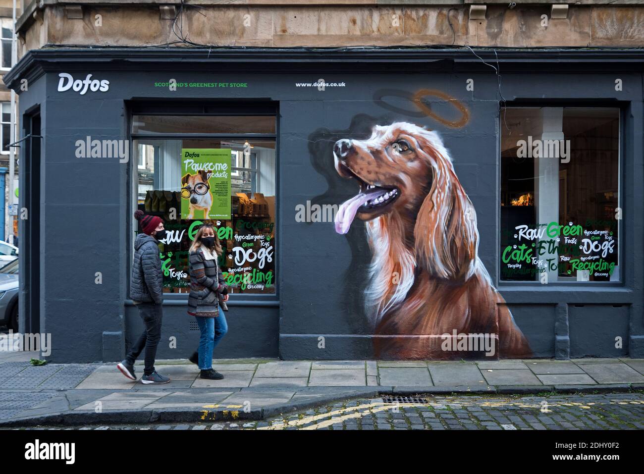 Young couple wearing face masks walking by Dofos Pet Shop in