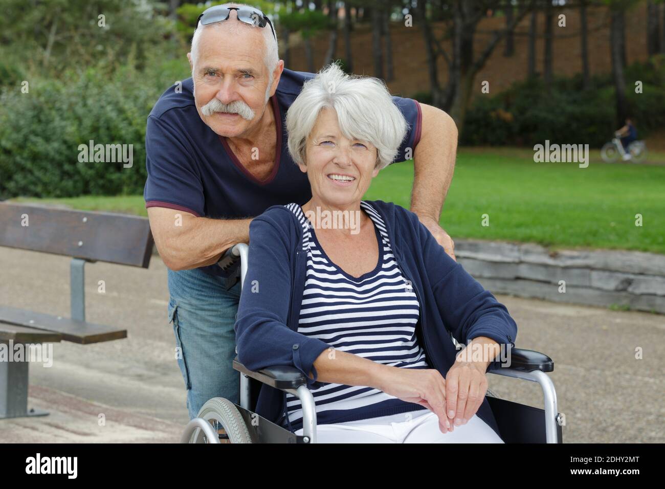 senior man and woman in wheelchair in park Stock Photo