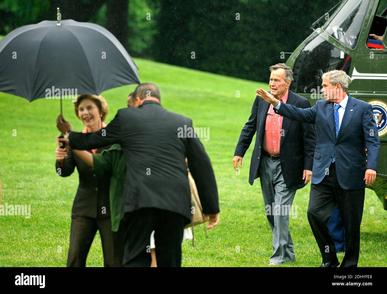 Former United States President George H.W. Bush (2nd,R) walks with US President George W. Bush as an aide assists first lady Laura Bush with an umbrella as they arrive at the White House from a weekend at the Crawford, Texas ranch, 11 May 2008 in Washington, DC, USA. Bush, whose daughter Jenna married Henry Hager at the ranch, described the experience as 'spectacular' and 'it's all we could have hoped for'. Photo by Mike Theiler/CNP/ABACAPRESS.COM Stock Photo
