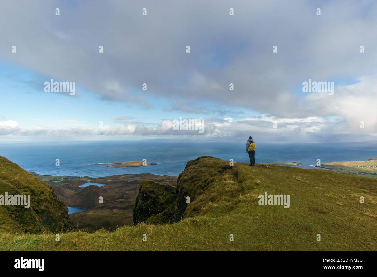 woman standing on the edge of a cliff watching at the sea on isle of Skye in the Quiraing, Scotland Stock Photo