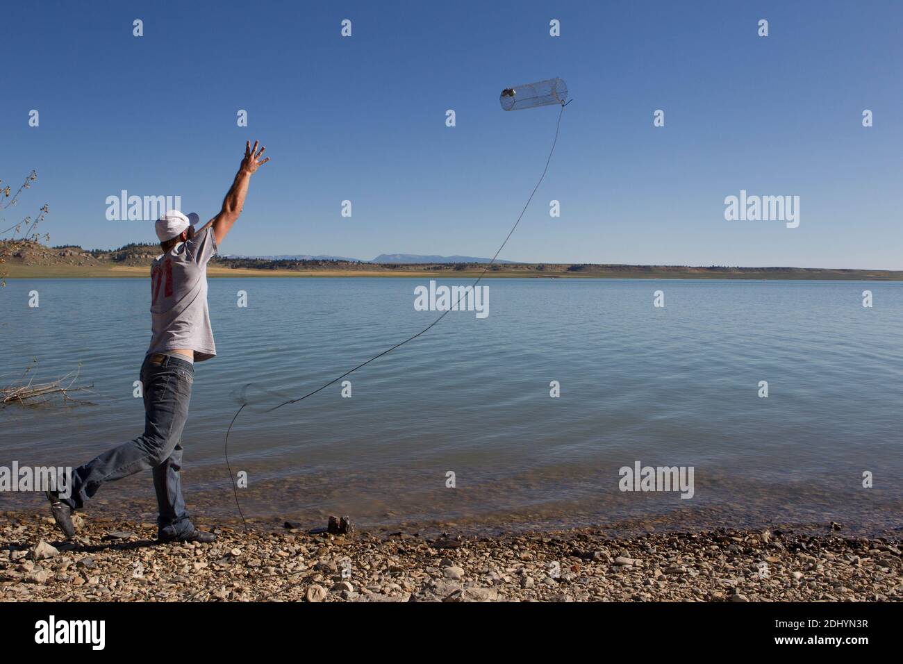 Fisherman tosses a crawdad trap into deeper water, Deadman's Basin, MT
