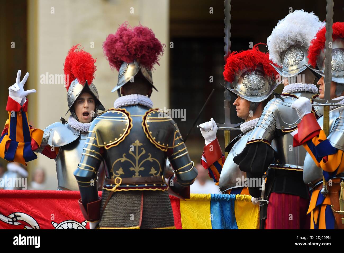 The Vatican's Swiss Guards swore in 23 new recruits on May 6, 2016 at the Vatican. The new recruits joined their ranks in an elaborate swearing-in ceremony . The ceremony is held each May 6 to commemorate the 147 Swiss Guards who died protecting Pope Clement VII during the 1527 Sack of Rome. Then each new recruit grasped the corps' flag and, raising three fingers in a symbol of the Holy Trinity, swore to uphold the Swiss Guard oath to protect pope Francis and his successors. The Swiss Guard, founded in 1506, consists of 100 volunteers who must be Swiss nationals, Catholic, single, at least 174 Stock Photo