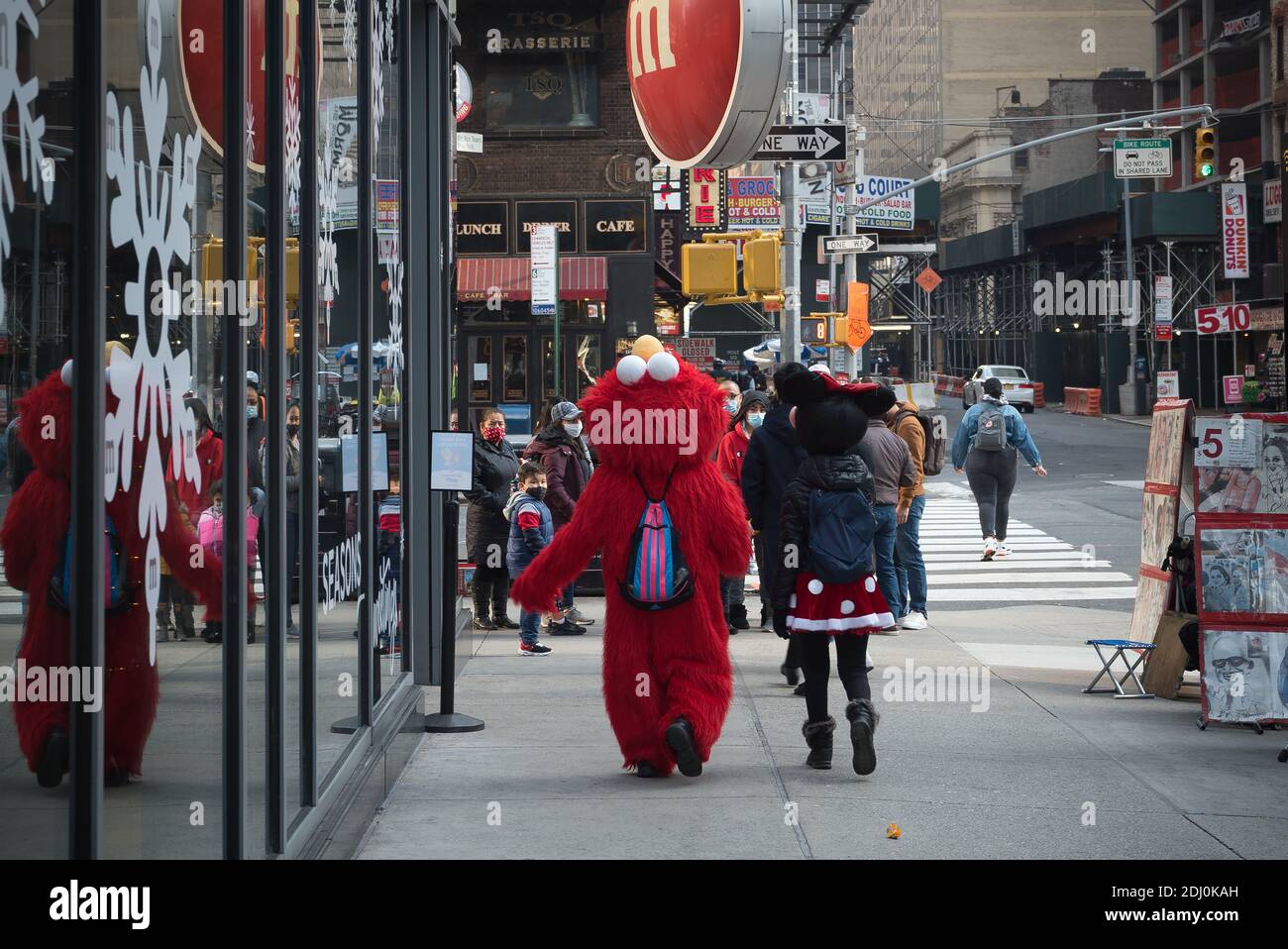Manhattan, New York. December 11, 2020. Times Square costumed characters meet a group of tourists in front of M&M store on 7th avenue. Stock Photo