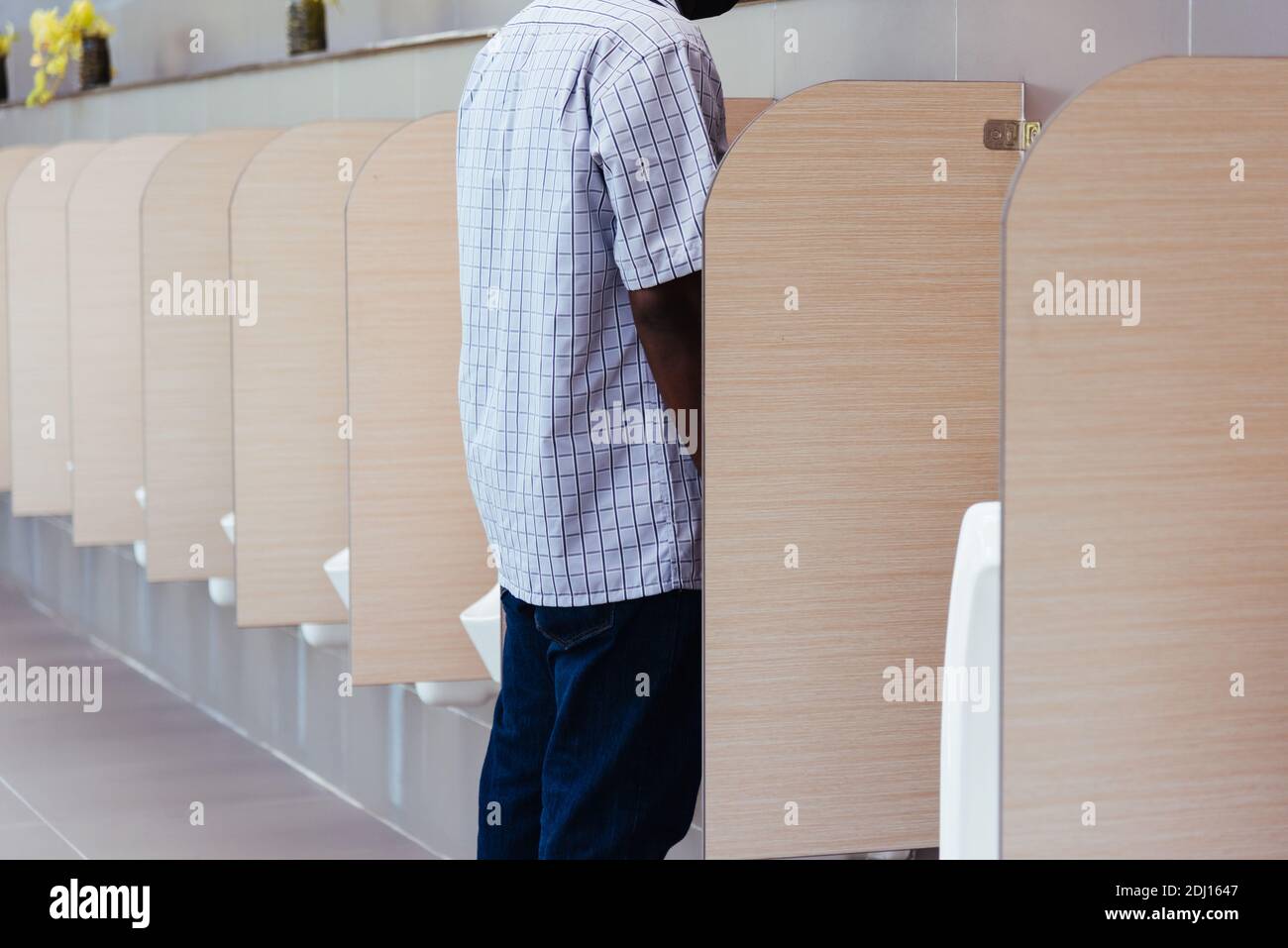 The man peeing in male toilet urinals bowl in restroom, wc Stock Photo