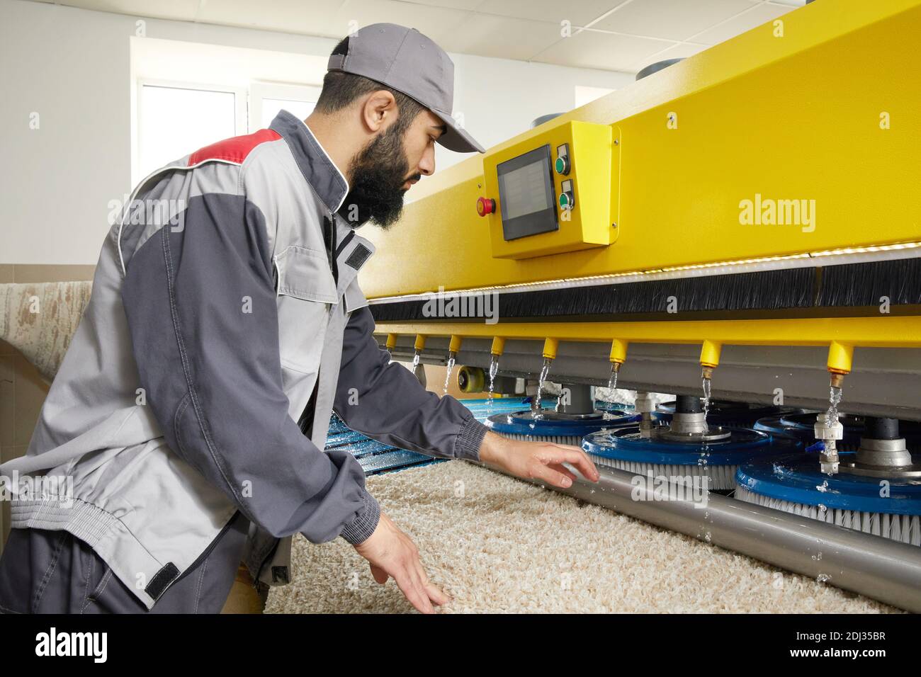 Man operating carpet automatic washing machine in professional laundry service Stock Photo