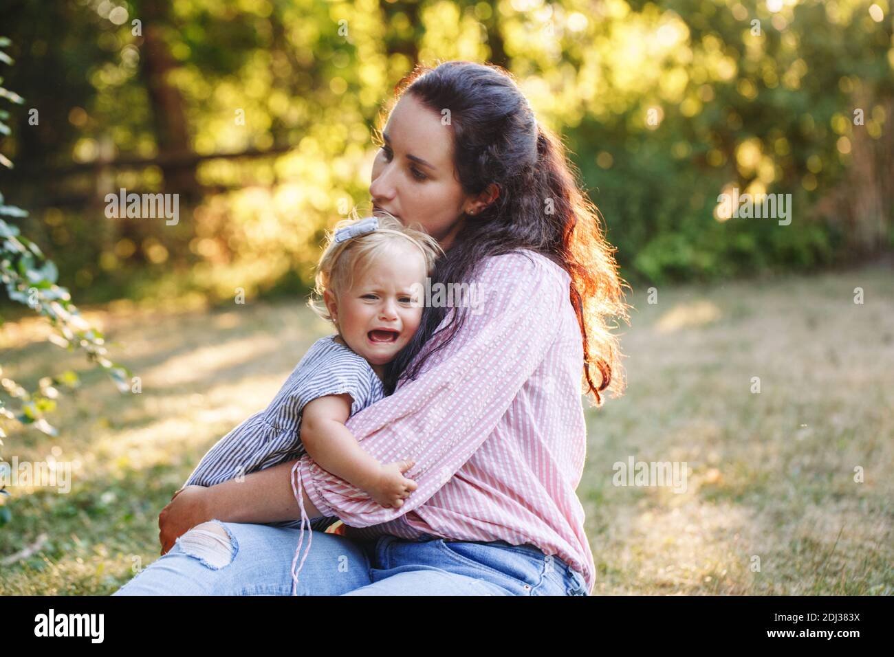 Mother hugging pacifying sad upset crying toddler girl. Family young