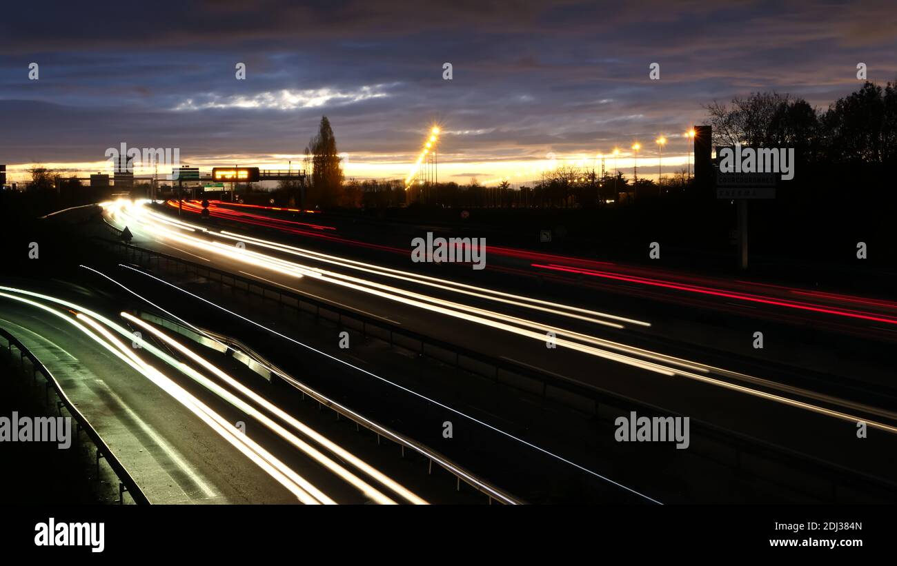 Light trail of cars on a highway during the morning. Spun vehicles on the road as seen from a bridge. Lightpainting scene. Stock Photo