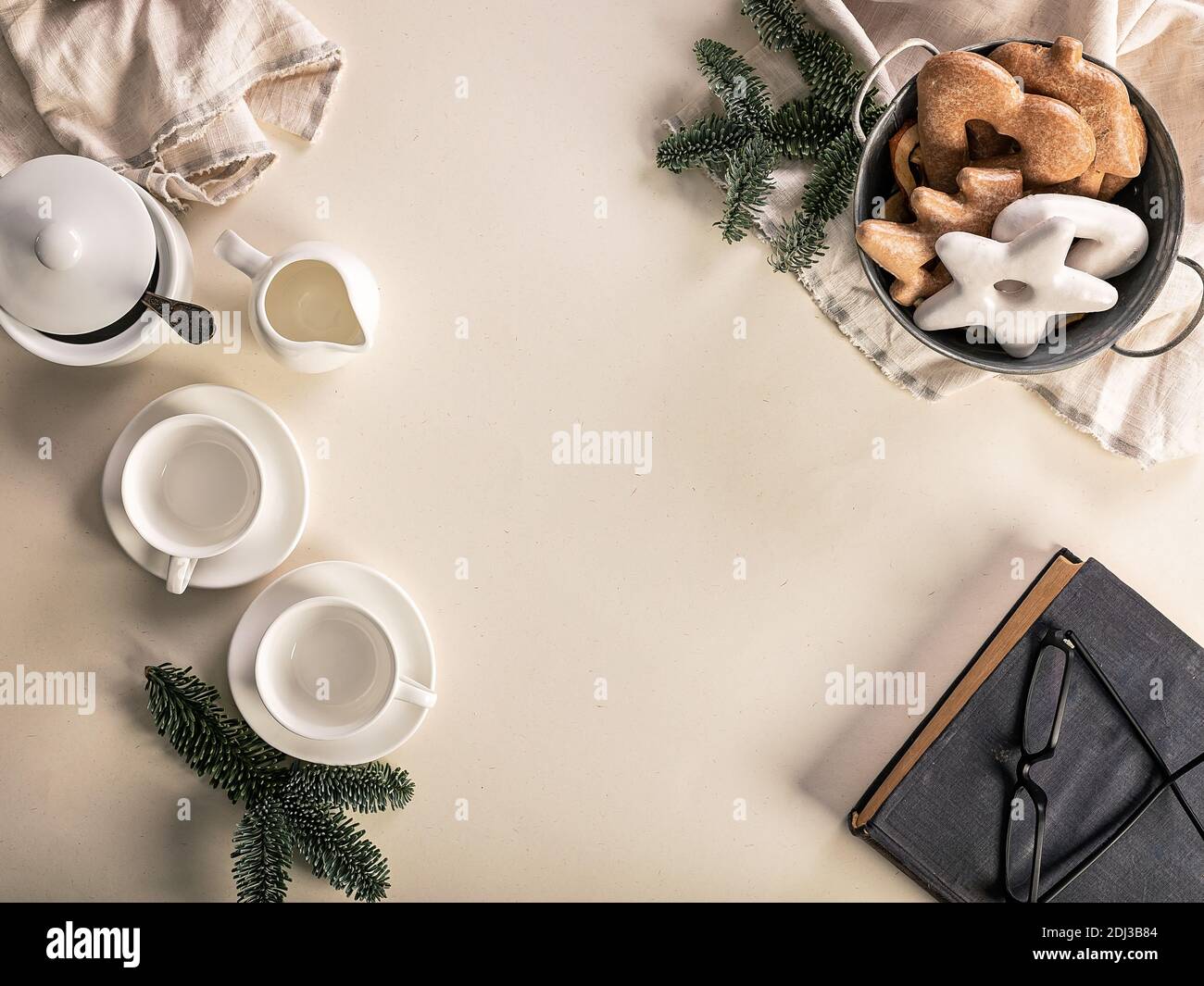 Christmas food flat lay. White coffee cups, gravy boat, basket with cookies and spruce branches on a beige background. Old book and glasses. Top view Stock Photo
