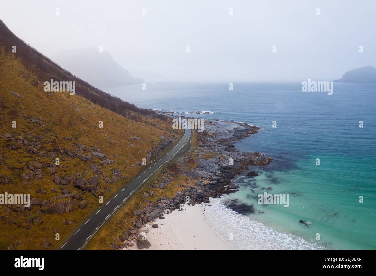 Drone shot, road between a mountain and in front of a fine sandy beach, Haukland beach, Lofoten, Norway Stock Photo