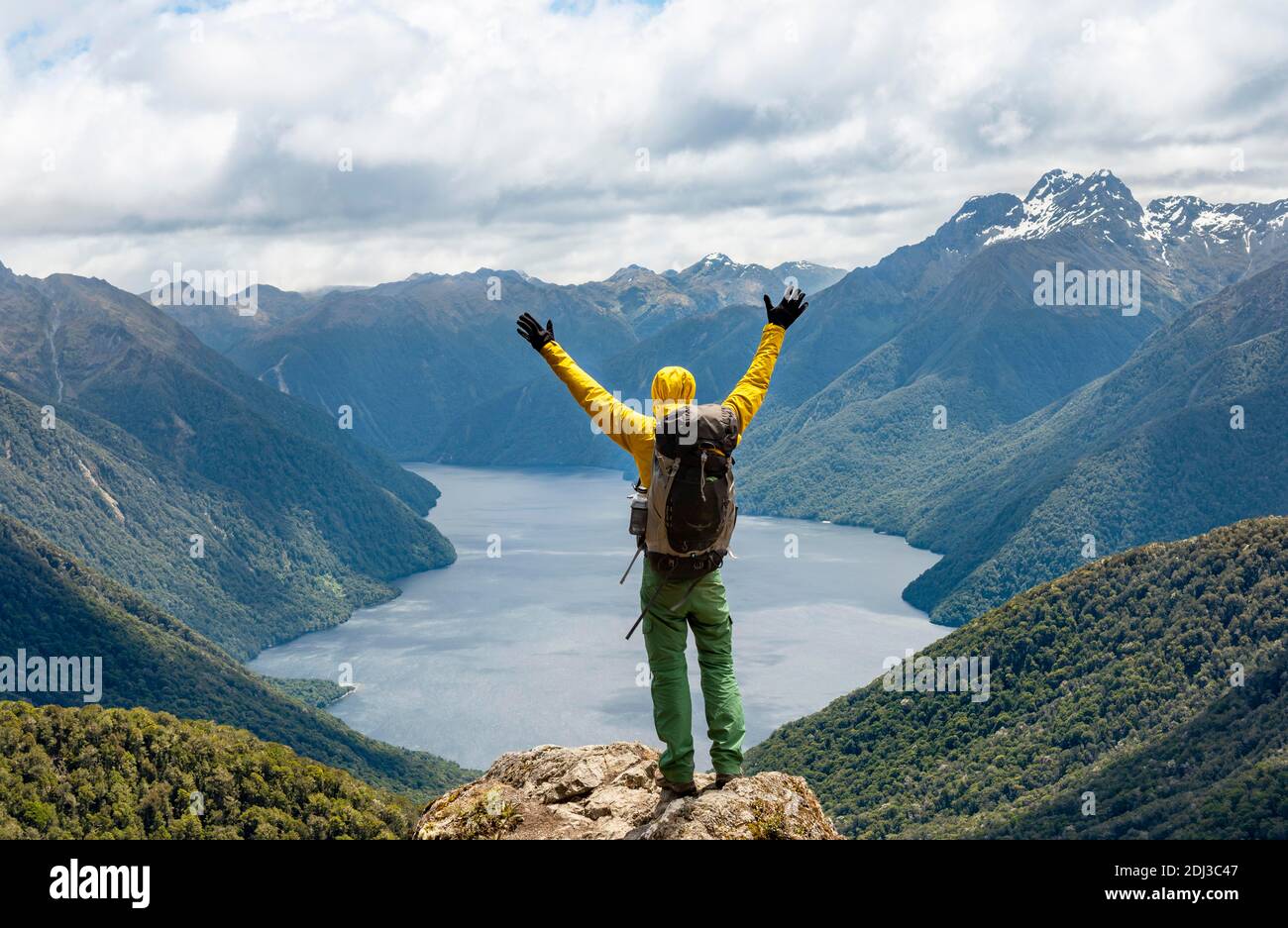 Mountaineer, hiker looks into the distance, stretching arms in the air, view of the South Fiord of Lake Te Anau, Murchison Mountains and Southern Stock Photo