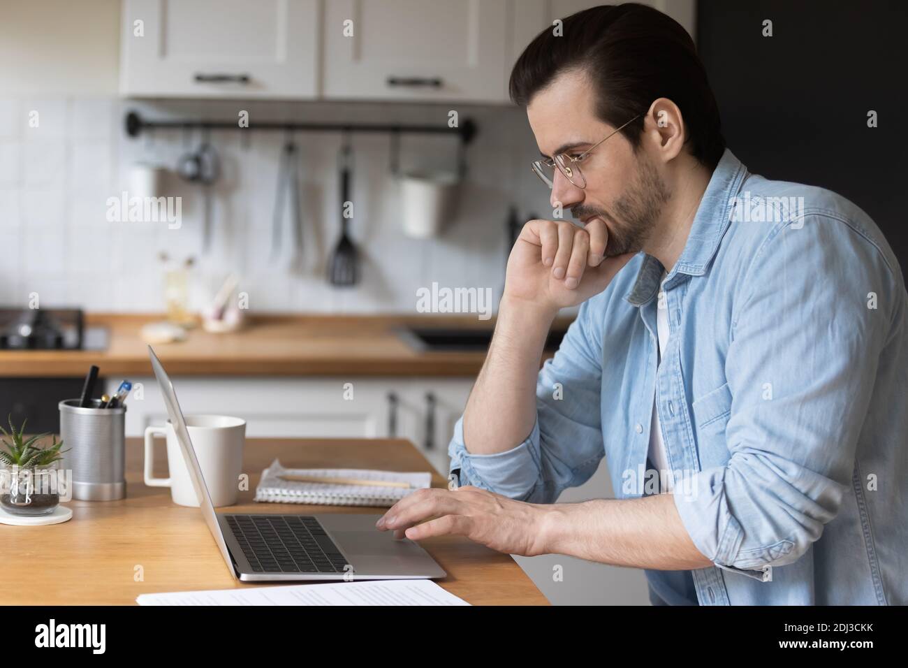 Close up thoughtful man touching chin using laptop, solving problem Stock Photo