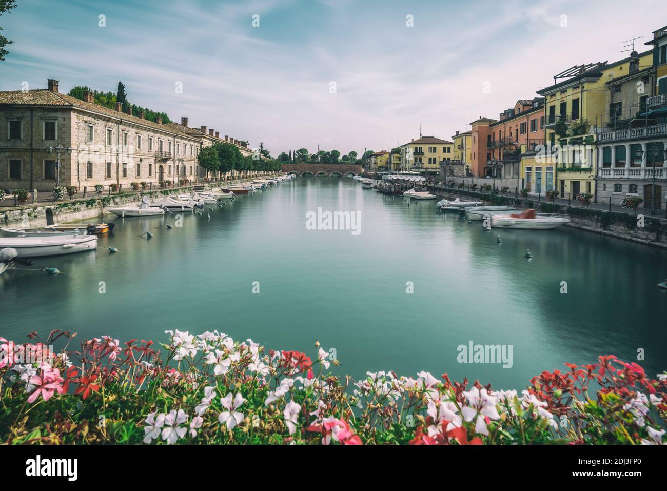 Colorful town of Peschiera del Garda with boats and blurred geranium flowers. The city is located at lake Lago di Garda,East of Venice, Italy, Europe. Stock Photo
