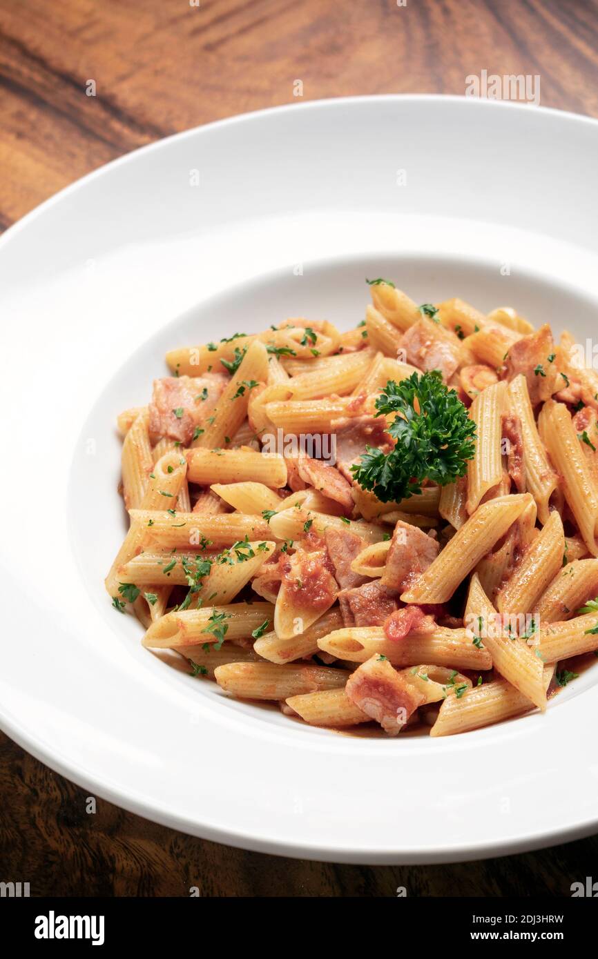 penne amatriciana tomato and ham sauce pasta on wood table background Stock Photo