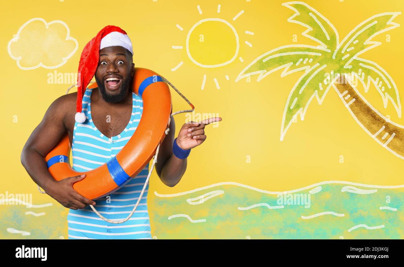Black man in swimsuit ready to go in a sunny place for christmas. Yellow background Stock Photo