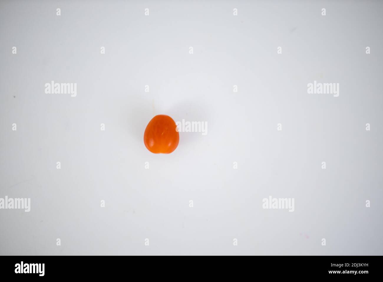 One cherry tomato isolated on a white table Stock Photo
