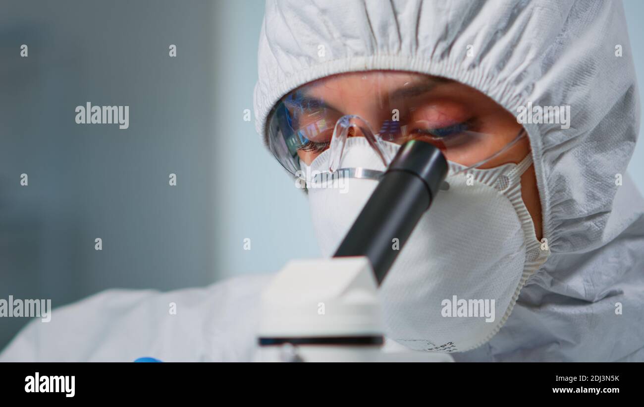 Close up of experienced biologist in ppe suit working on microscopes in
