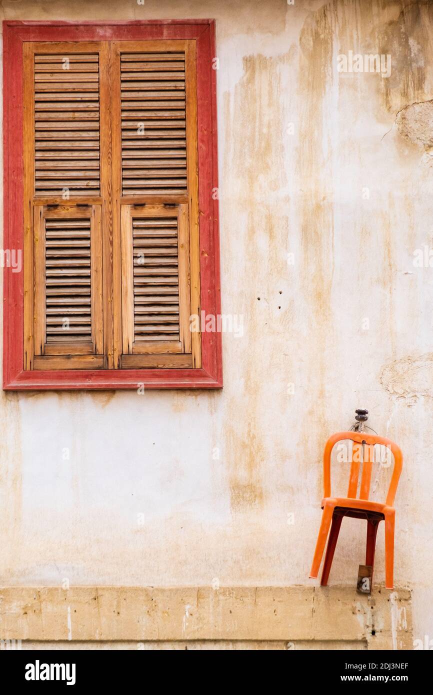 Orange chair hanging on the wall and beautiful wooden window of a