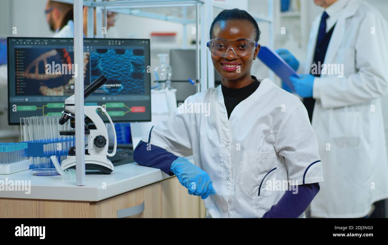 Docter Using Science Black doctor woman smiling at camera sitting in scientific modern ...