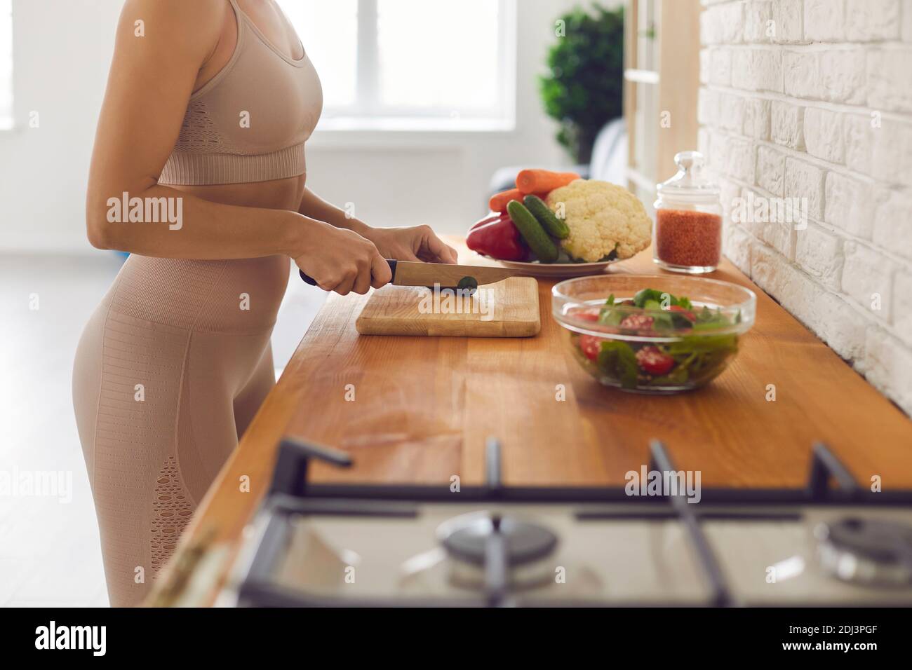 Unrecognizable fit woman standing at countertop and chopping vegetables for healthy salad Stock Photo