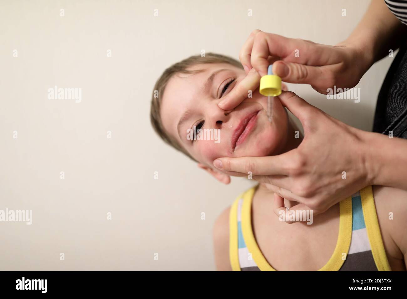 Person treats the boy runny nose at home Stock Photo