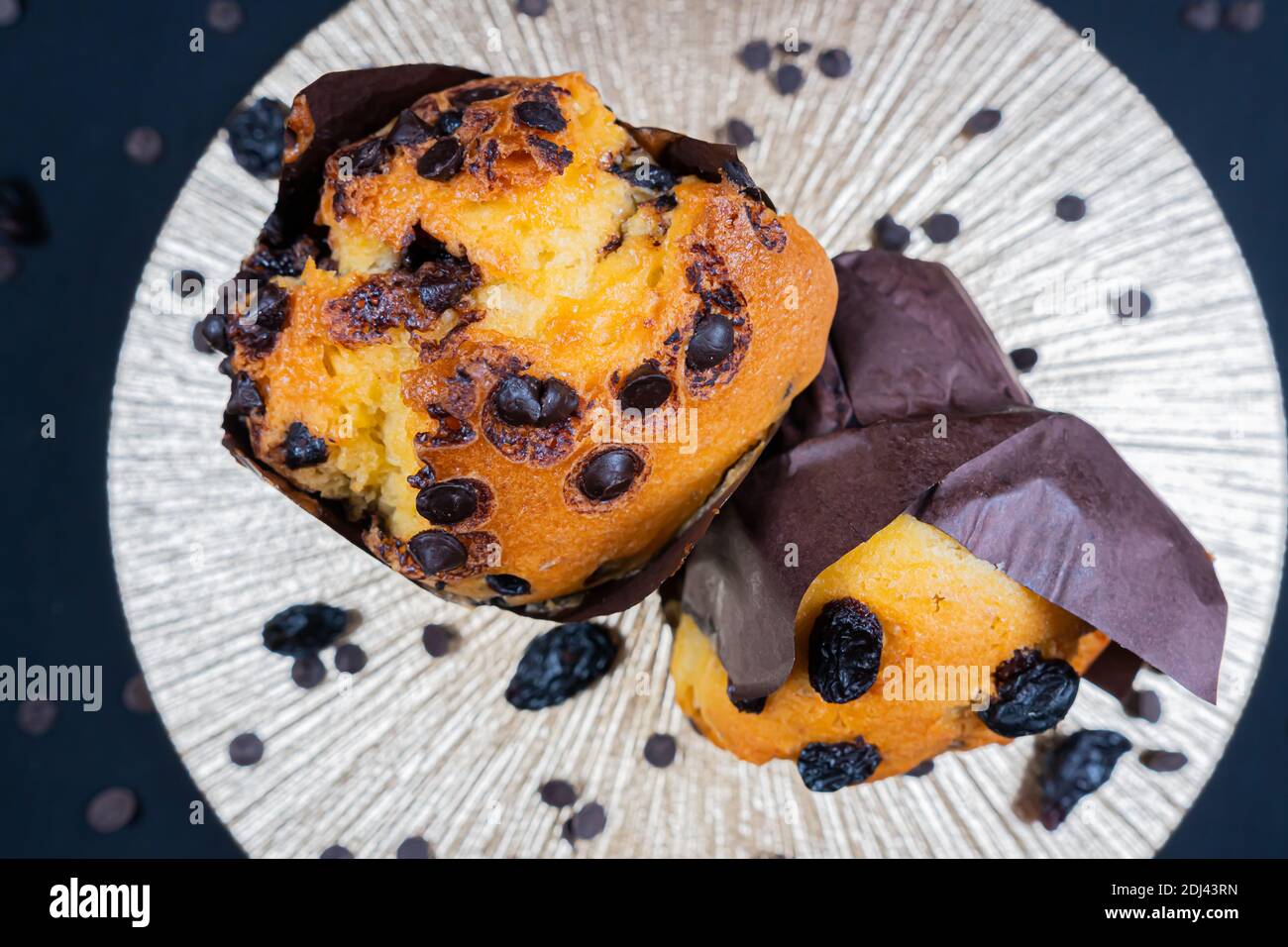 Chocolate, raisin chips and chocolate raisin muffin on a white plate. black background. Copyspace Stock Photo