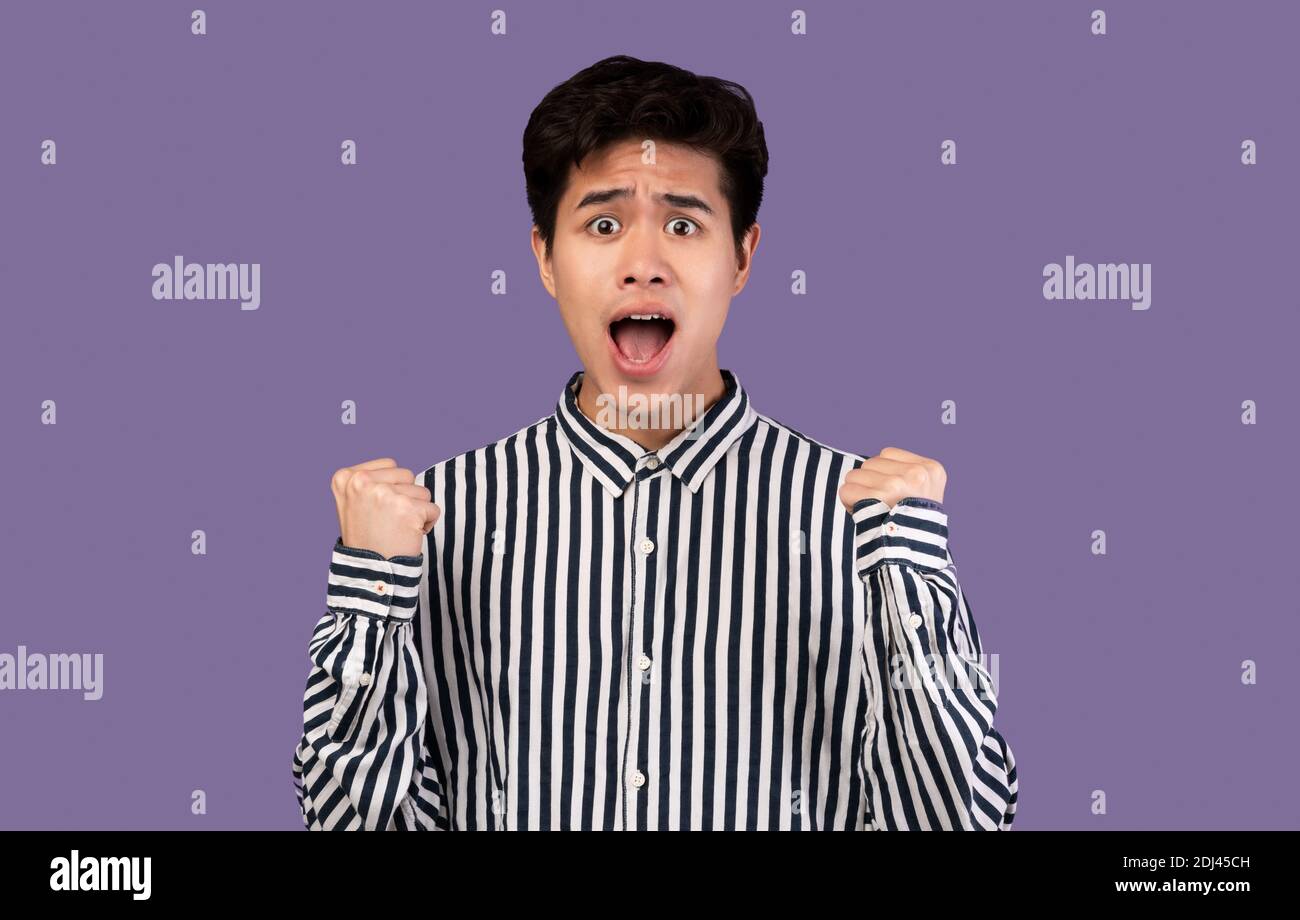 Portrait of excited asian man screaming with raised fists Stock Photo