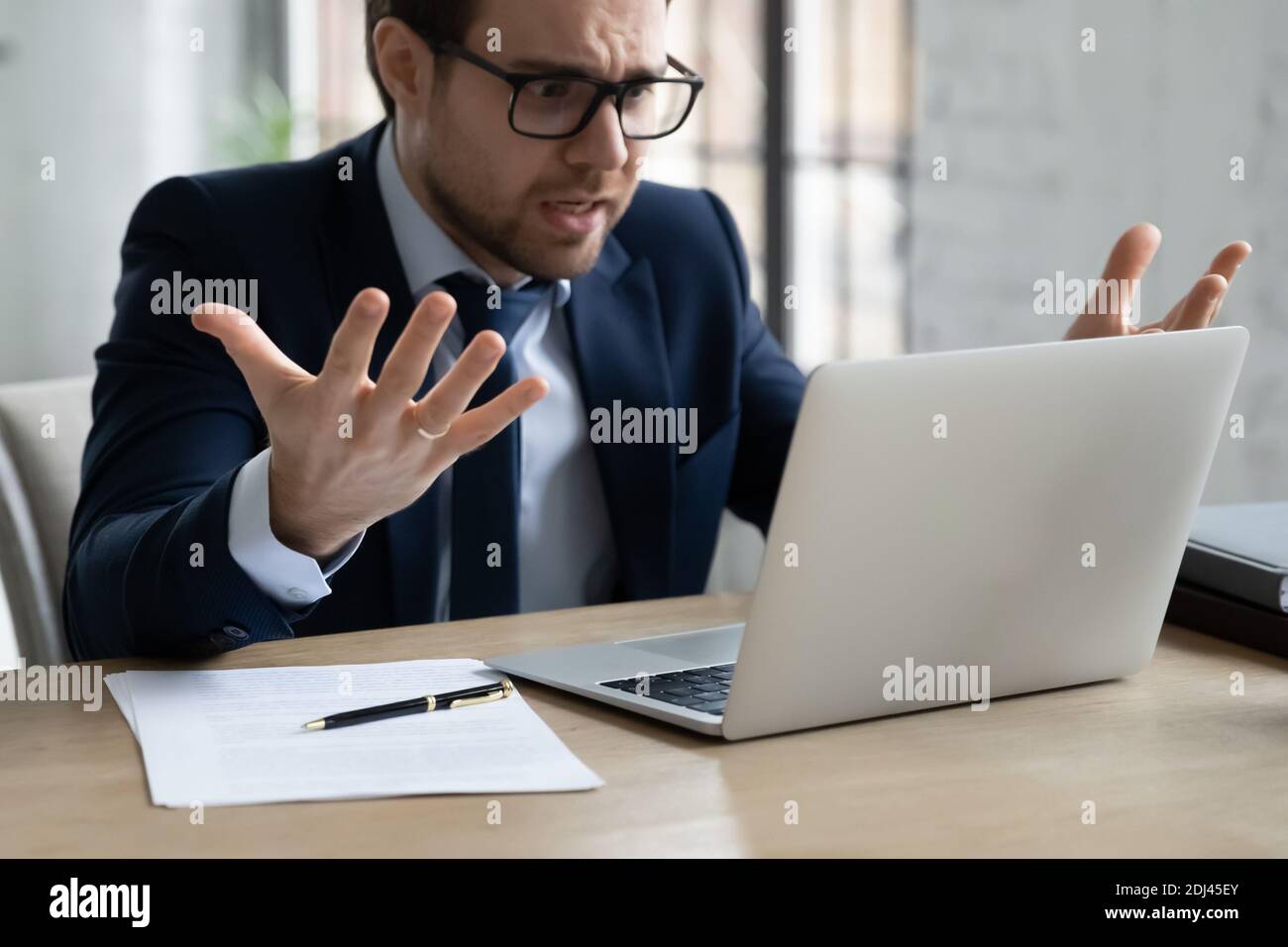 Close up annoyed businessman wearing glasses looking at laptop screen Stock Photo