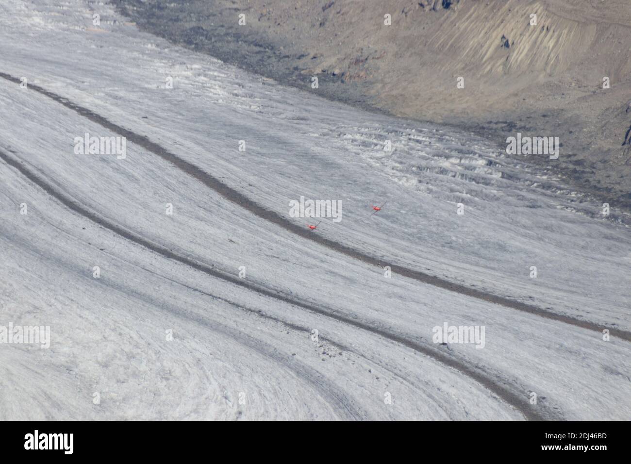 two airplanes fly above the aletsch glacier in Switzerland Stock Photo