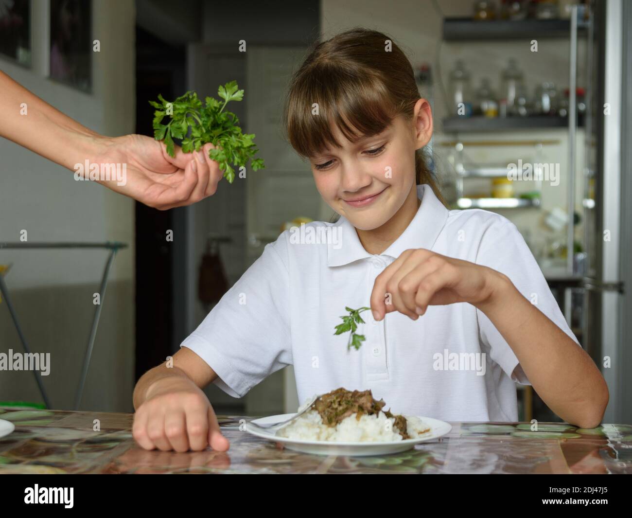 Girl sprinkles fresh herbs on the second dish for lunch Stock Photo