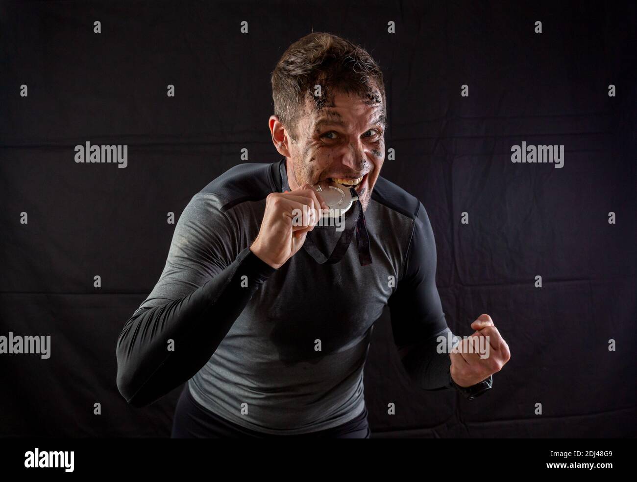 Handsome man in sportswear is insanely rejoicing at the received silver medal in the studio on a black background Stock Photo